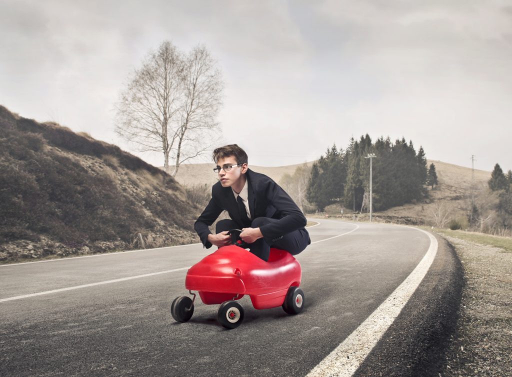 professional-looking guy riding in a toy car