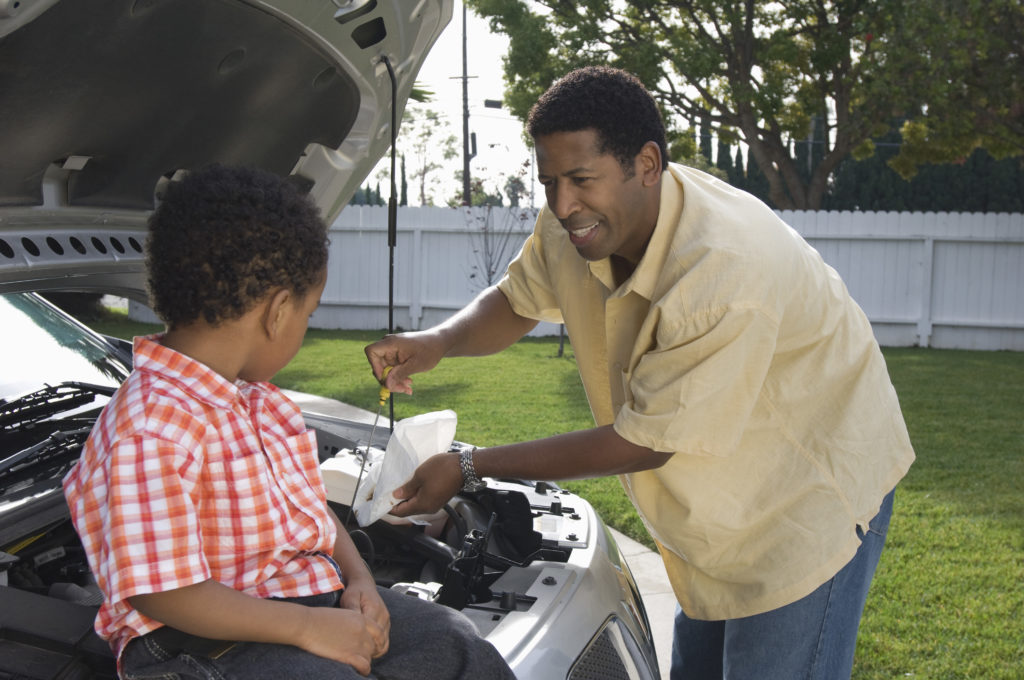 a son helping his dad change the car’s oil