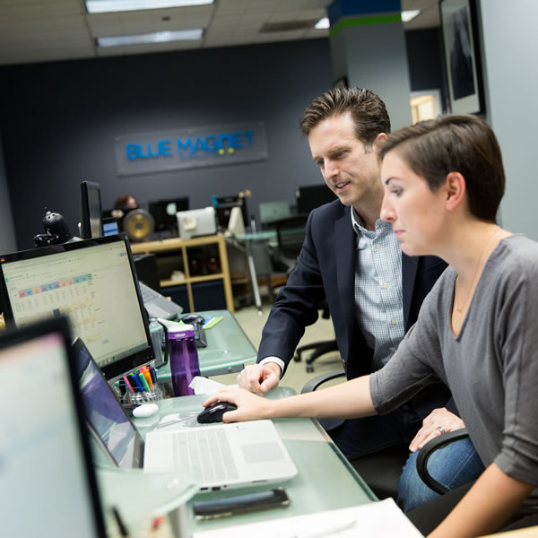 two digital marketers discuss strategy in front of a laptop