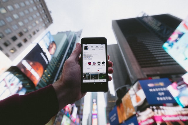 hand holding up smartphone with instagram in Times Square NYC